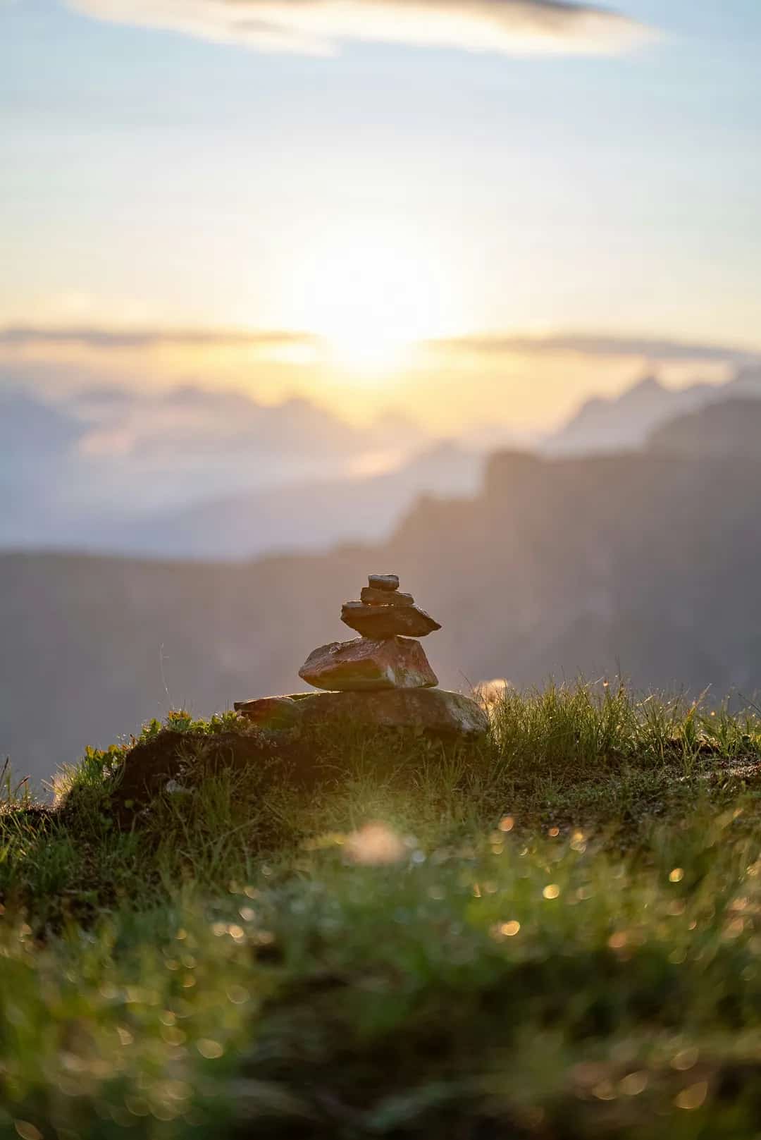 A stone cairn above the Dolomite valleys at first light
